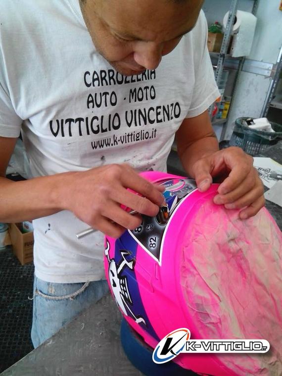 Mani che staccano il nastro da un casco fucsia e blu con un teschio dipinto