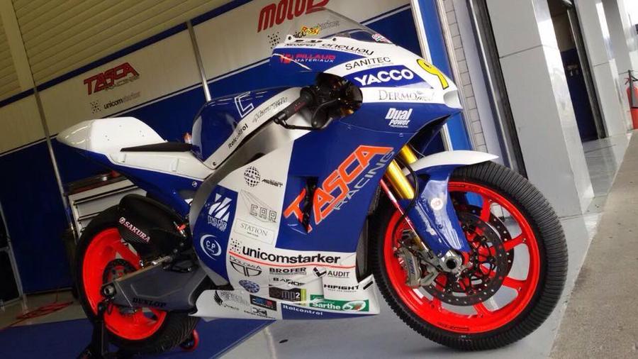 Moto da corsa bianca e blu con la carena decorata, ferma in un box
